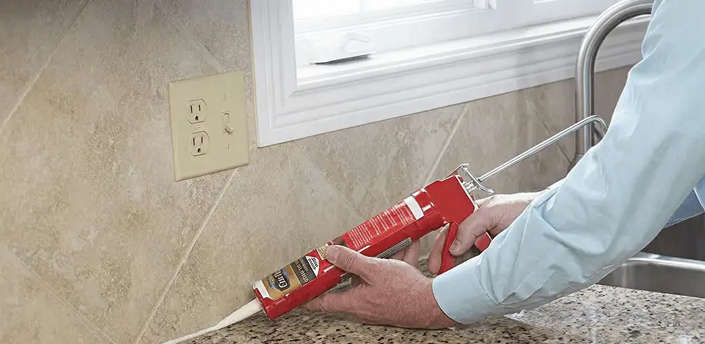 Handyman applying caulk along a kitchen backsplash and countertop seam in Eugene, OR