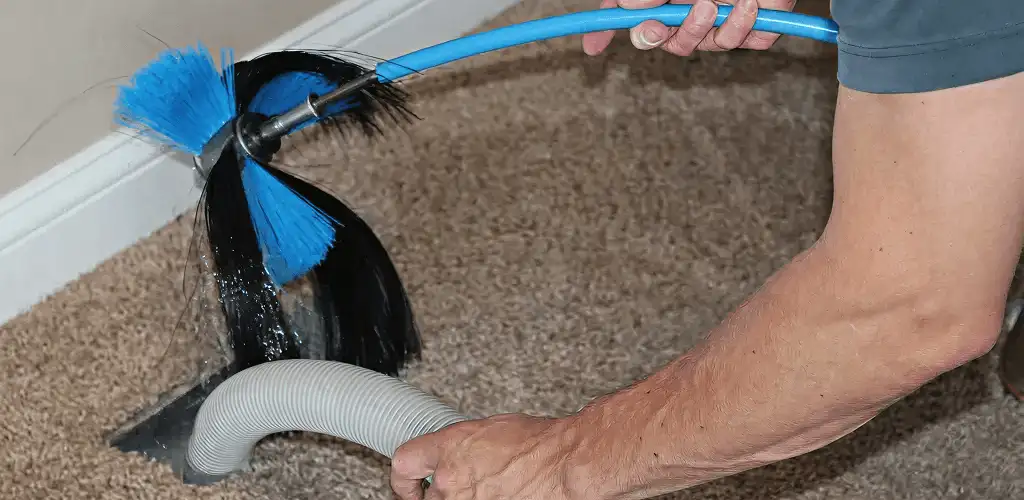 Dryer vent cleaning technician brushing lint from a vent line in Eugene, OR