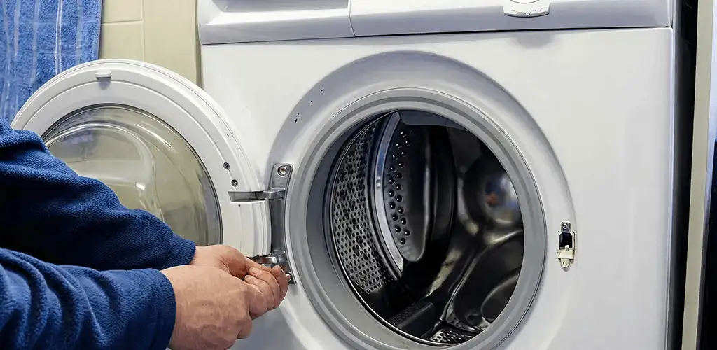 Washing machine repair handyman checking a front-load washer door and latch in Eugene, OR