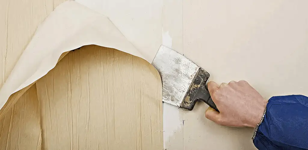 Handyman removing wallpaper with a scraper for wall preparation in Eugene, OR