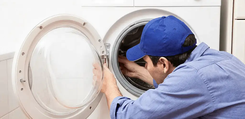 Washing machine repair handyman inspecting a front-load washer drum in Eugene, OR