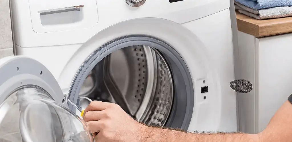 Handyman repairing a front-load washing machine and inspecting the drum in Eugene, OR