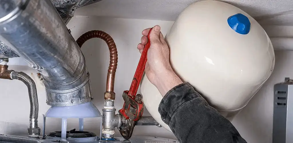 Water heater repair technician tightening plumbing connections near a tank unit in Eugene, OR