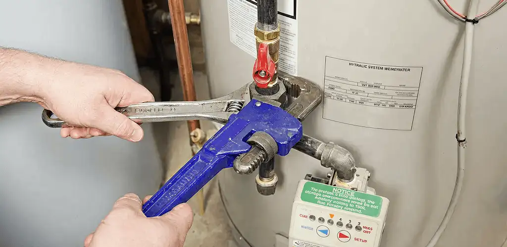 Water heater repair technician tightening the shutoff valve and supply line in Eugene, OR